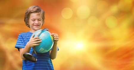 Digital composite of Smiling boy looking at globe over bokehの写真素材