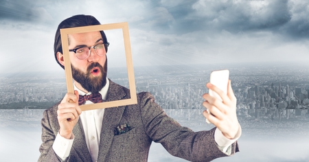 Digital composite of Hipster holding frame while taking selfie on mobile phoneの写真素材