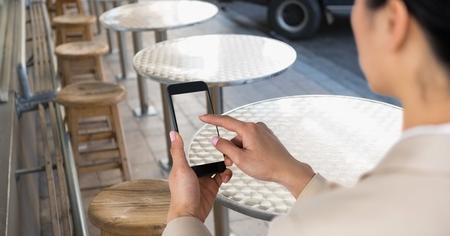 Digital composite of Businesswoman taking picture with mobile phone in coffee shop