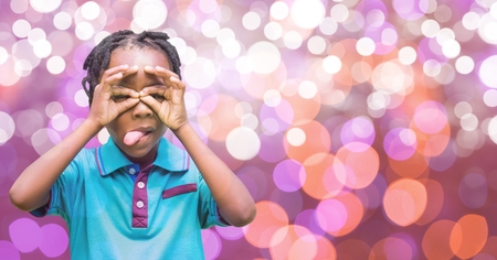 Digital composite of Playful boy sticking out tongue over bokehの写真素材