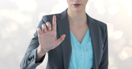 Digital composite of Midsection of businesswoman touching imaginary screen over bokehの写真素材