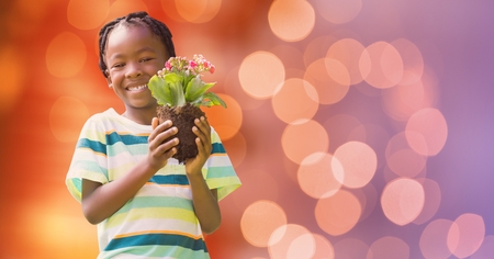 Digital composite of Portrait of happy boy holding flower pot over bokehの写真素材