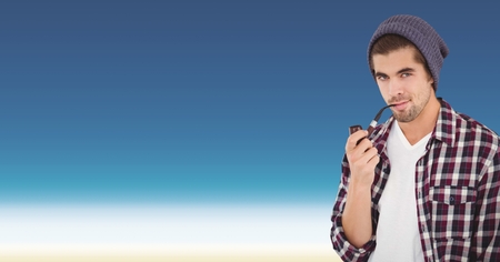 Digital composite of Confident male hipster smoking pipe against blue backgroundの写真素材