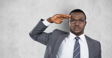 Digital composite of Portrait of confident businessman saluting against gray backgroundの写真素材