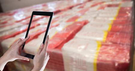 Digital composite of Hands taking picture with tablet PC in warehouseの写真素材