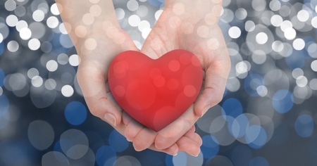 Digital composite of Cropped image of female's hands holding heart shape over bokehの写真素材