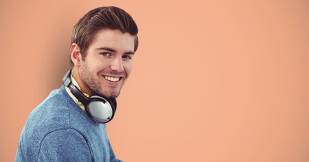 Digital composite of Smiling male hipster with headphones against orange background