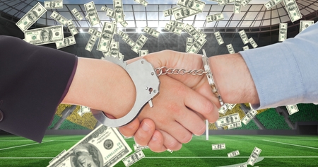 Digital composite of Business people with handcuffs shaking hands at football stadium representing corruptionの写真素材