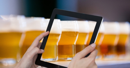 Digital composite of Hands photographing beer glasses through digital tablet at barの写真素材