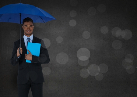 Digital composite of Business man with umbrella and blue book against grey wall and bokehの写真素材