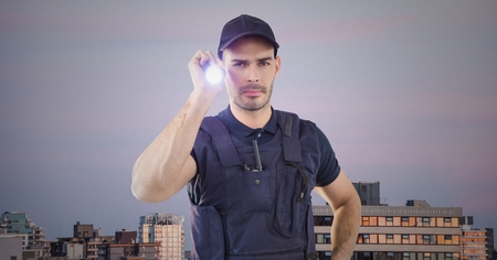 Digital composite of Security guard with flashlight against buildings and purple skyの写真素材