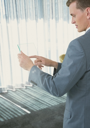 Digital composite of Businessman touching phone in office by window lightの写真素材