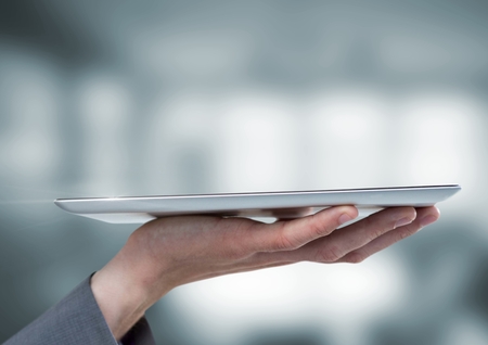 Digital composite of Hand holding tablet with blur background