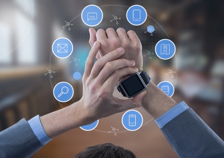 Digital composite of Businessman holding watch with apps icons in large room