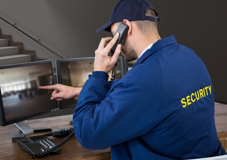 Digital composite of security guard in his office phoning and pointing something in the screen