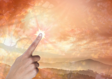 Digital composite of Hand touching orange skyの写真素材