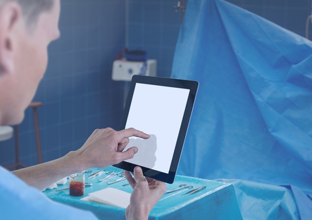 Digital composite of Doctor holding tablet in surgery room