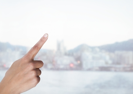 Digital composite of Hand touching air with bright city backgroundの写真素材