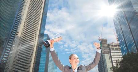 Digital composite of businesswoman with trophy in her hand. In te cityの写真素材