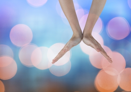Digital composite of Hands open in a V shape with sparkling light bokeh background