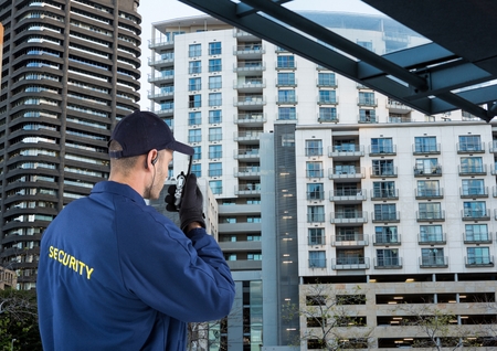 Digital composite of security guard speaking with walkie-talkie. City