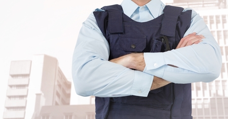 Digital composite of Security guard mid section arms folded against faded buildings