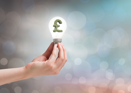 Digital composite of Hands holding lightbulb with money symbol with sparkling light bokeh backgroundの写真素材