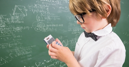 Digital composite of Boy with calculator against green chalkboard with math doodles