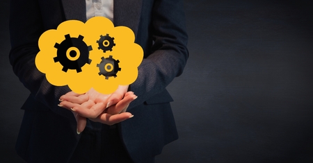 Digital composite of Business woman mid section with yellow cloud and gear graphic in hands against navy backgroundの写真素材