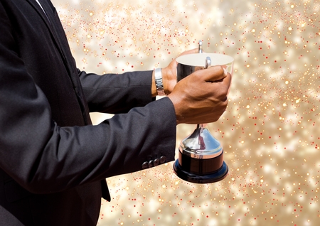 Digital composite of business hand with trophy, golden back