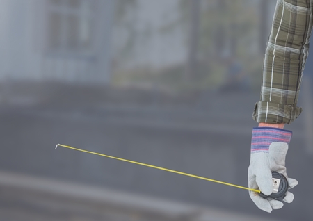 Digital composite of Hand with measuring tape on building siteの写真素材