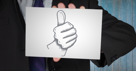 Digital composite of Business man mid section with card showing thumbs up doodle against blue wood panelの写真素材