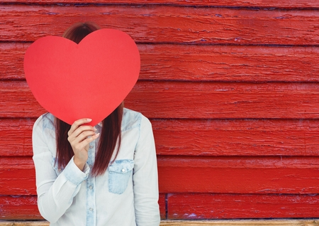 Digital composite of hipster woman  with the face covered with a heart.  red wood backgroundの写真素材