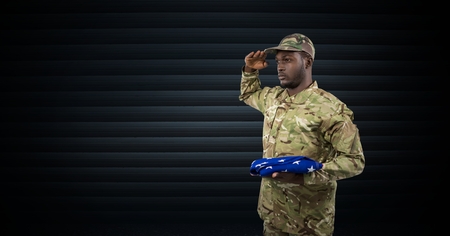 Digital composite of soldier saluting with the USA flag in his hand. dark backgroundの写真素材