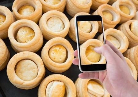 Digital composite of Hand of person taking a picture of cakes with her smartphoneの写真素材