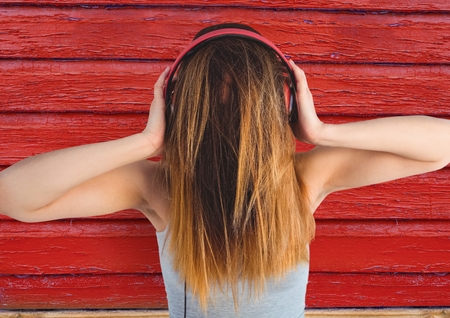Digital composite of hipster woman listening music with red wood backgroundの写真素材