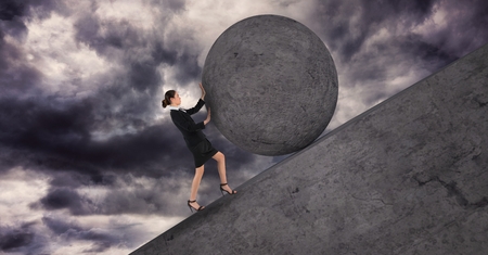 Digital composite of Businesswoman pushing a 3D stone ball above herの写真素材