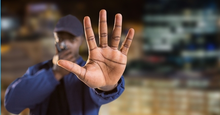 Digital composite of Security guard talking on walkie talkie with hand gesturing to stop while...