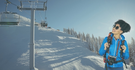 Digital composite of Hiker looking at ski lift while standing on snow covered mountainの写真素材