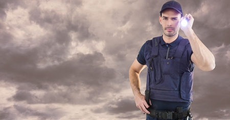 Digital composite of Portrait of security guard holding flashlight against cloudy skyの写真素材