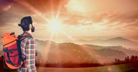 Digital composite of Hipster carrying backpack with camera and looking at mountains while standing...