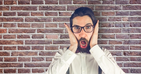 Digital composite of Creative businessman looking surprised while standing against brick wall