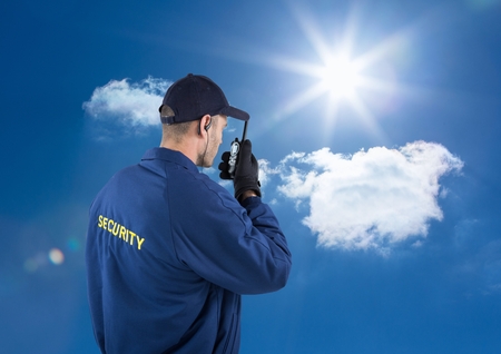 Digital composite of Rear view of security guard talking on walkie talkie against sky