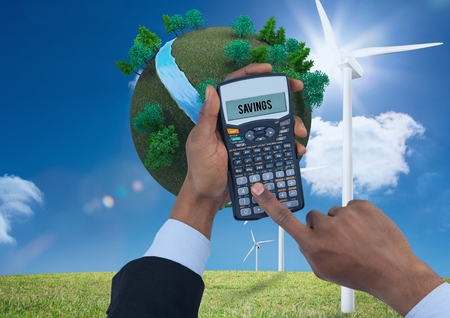 Digital composite of Digital composite image of hands using calculator with planet earth and windmills on grassy field agの写真素材