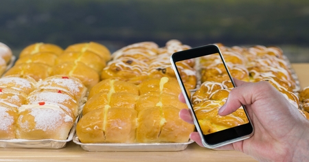 Digital composite of Cropped hand taking picture of dessert through smart phone at bakery