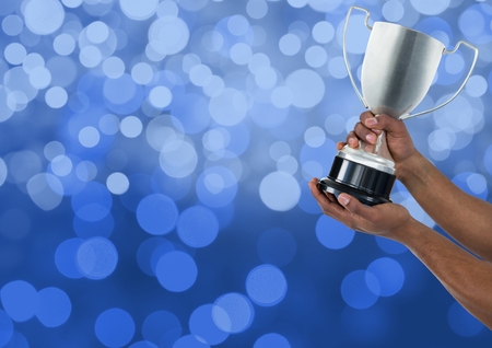 Digital composite of Hands holding trophy against bokehの写真素材