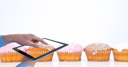 Digital composite of Cropped hands photographing muffins through digital tabletの写真素材