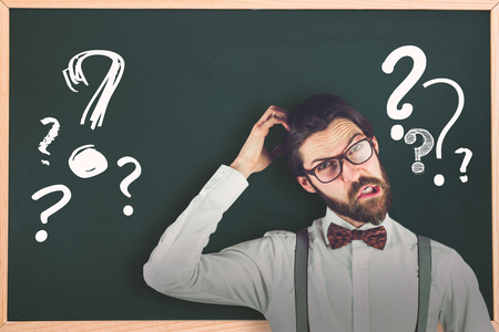 Portrait of confused man scratching head against question markの写真素材