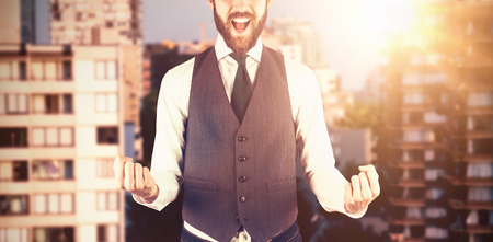 Portrait of cheerful businessman against trees growing amidst buildingsの写真素材