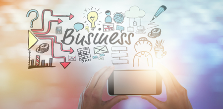 Cropped hands of businesswoman holding mobile phone against glowing backgroundの写真素材